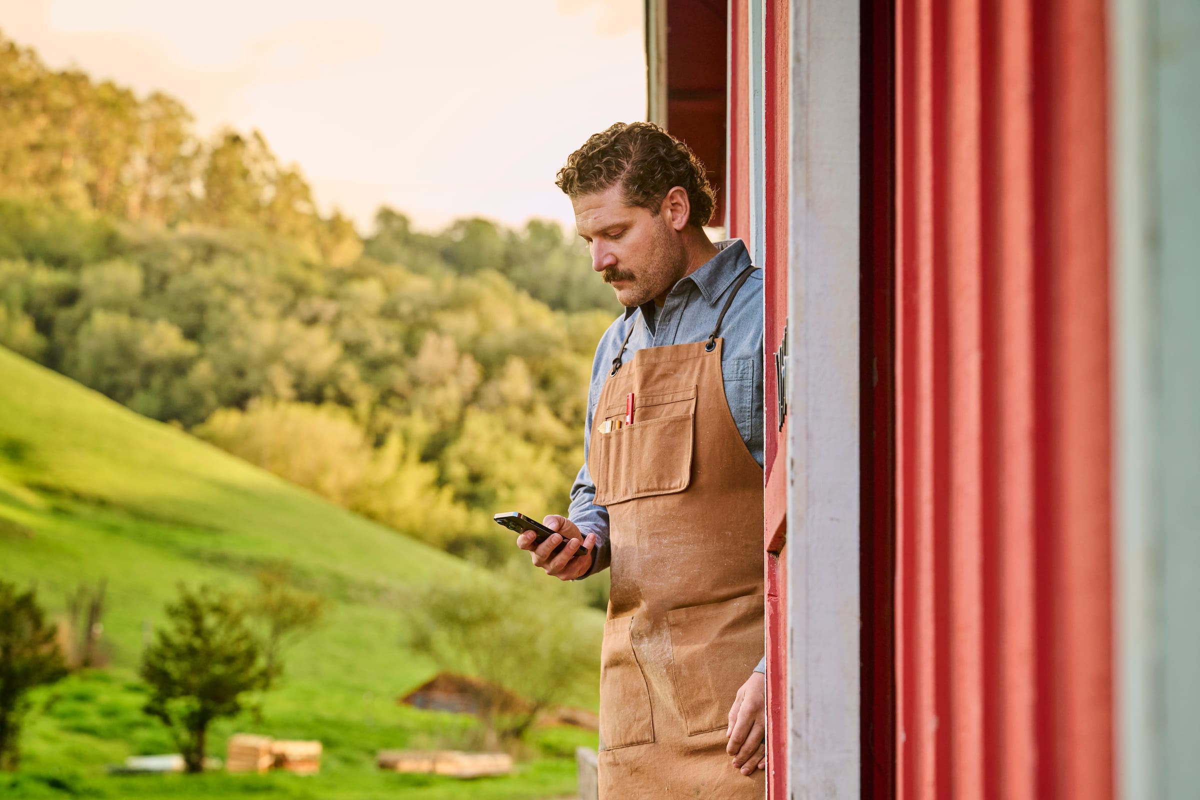 One person slices fruit while another does their accounting with their smartphone using Xero, the QuickBooks software alterna