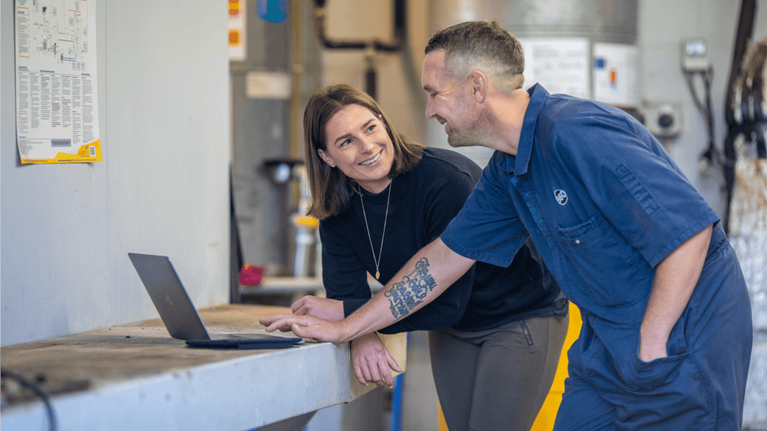 A tradesperson shares a moment with a colleague while using business accounting software to invoice for the job.