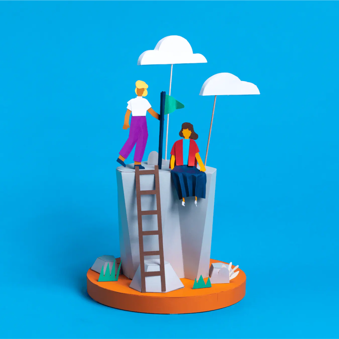 One person standing and another sitting at a high vantage point that they've reached by climbing a ladder.